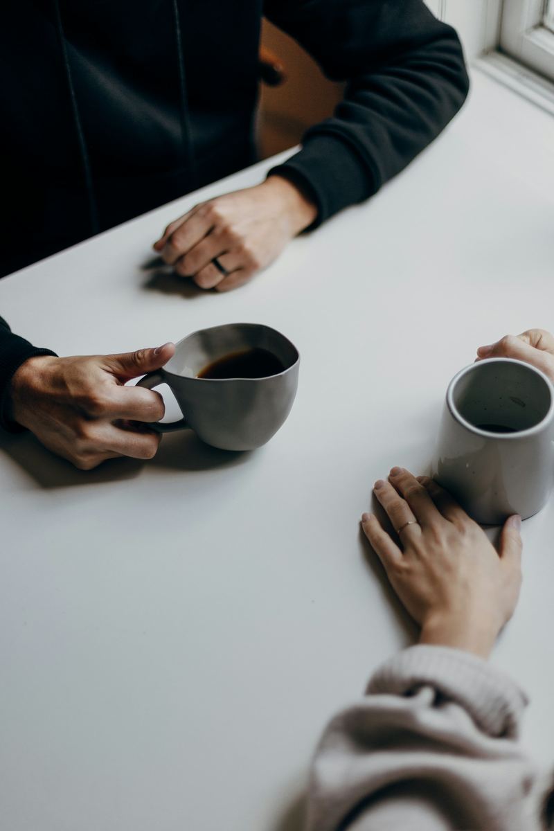 Twee mensen in gesprek aan tafel met een kop koffie